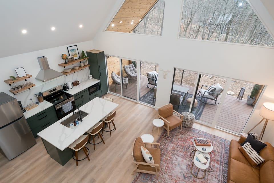 Bask in natural light and pond views from this stylish open-concept living area—featuring a fully equipped kitchen, cozy seating, and direct access to the outdoor deck.