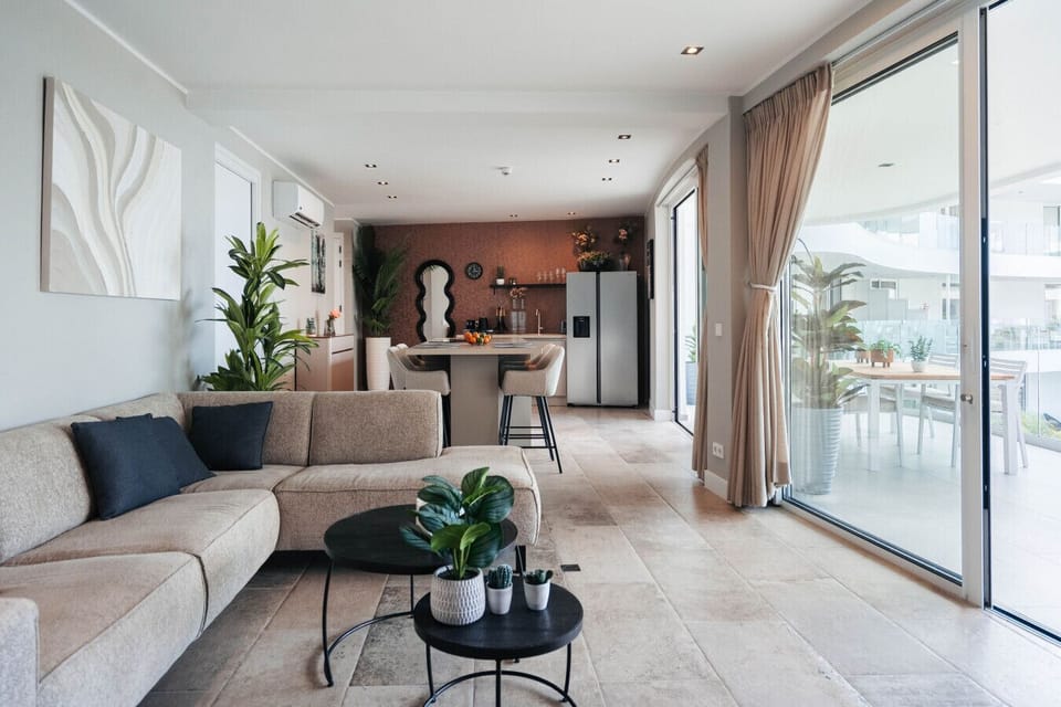 Spacious open-plan living area with a cozy lounge, modern kitchen, and sliding doors leading to the balcony.