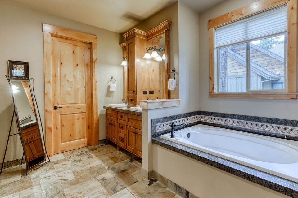 Bathroom featuring a deep soaking tub, natural wood vanity, and tile floors.