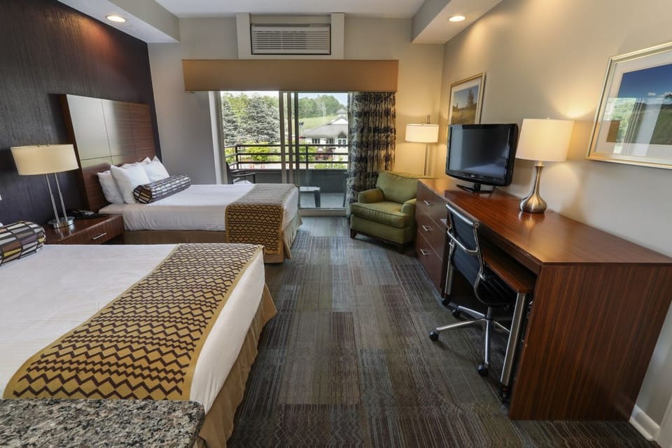 Spacious room with two beds, a seating area, and convenient workspace, ideal for work or leisure.