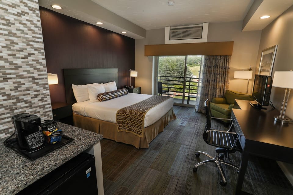Comfortable guest room with a plush bed, work desk, and plenty of natural light from large windows.
