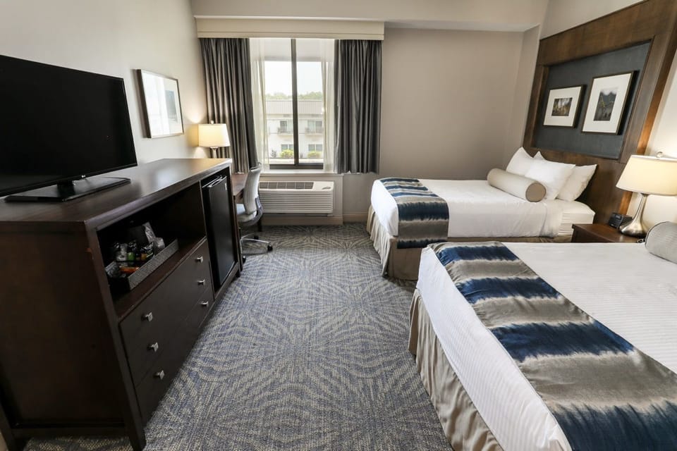 Spacious guest room featuring two beds, a flat-screen TV, and seating area for added comfort.