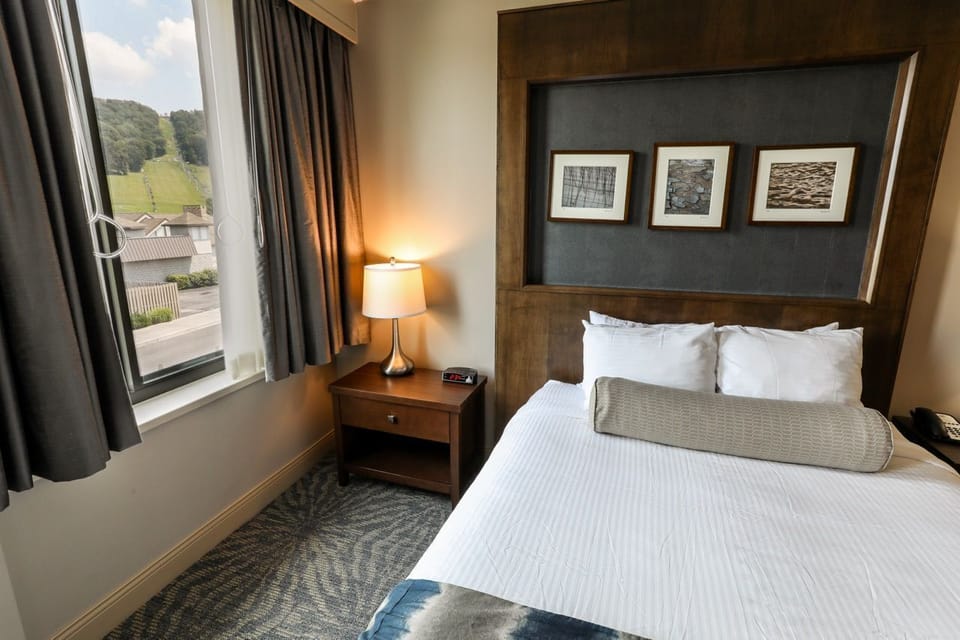 Cozy room with a comfortable bed and large windows, offering scenic views.