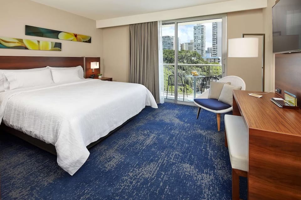 Unwind in a crisp king bed beside bright balcony doors.