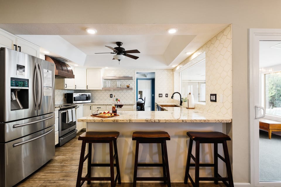 The fully equipped modern kitchen is stocked with all culinary essentials, stainless-steel appliances, and breakfast bar seating.