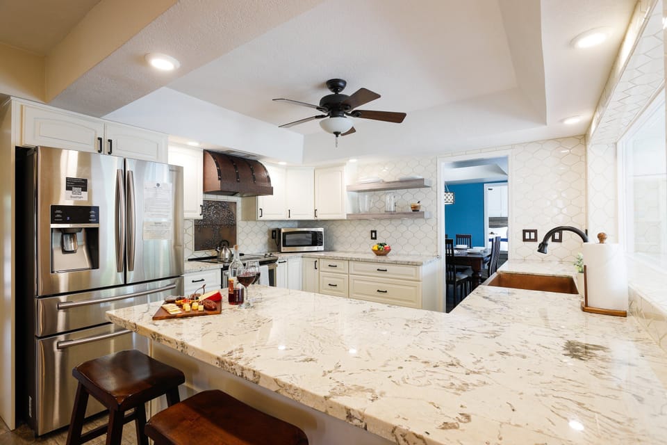 The fully equipped modern kitchen is stocked with all culinary essentials, stainless-steel appliances, and breakfast bar seating.