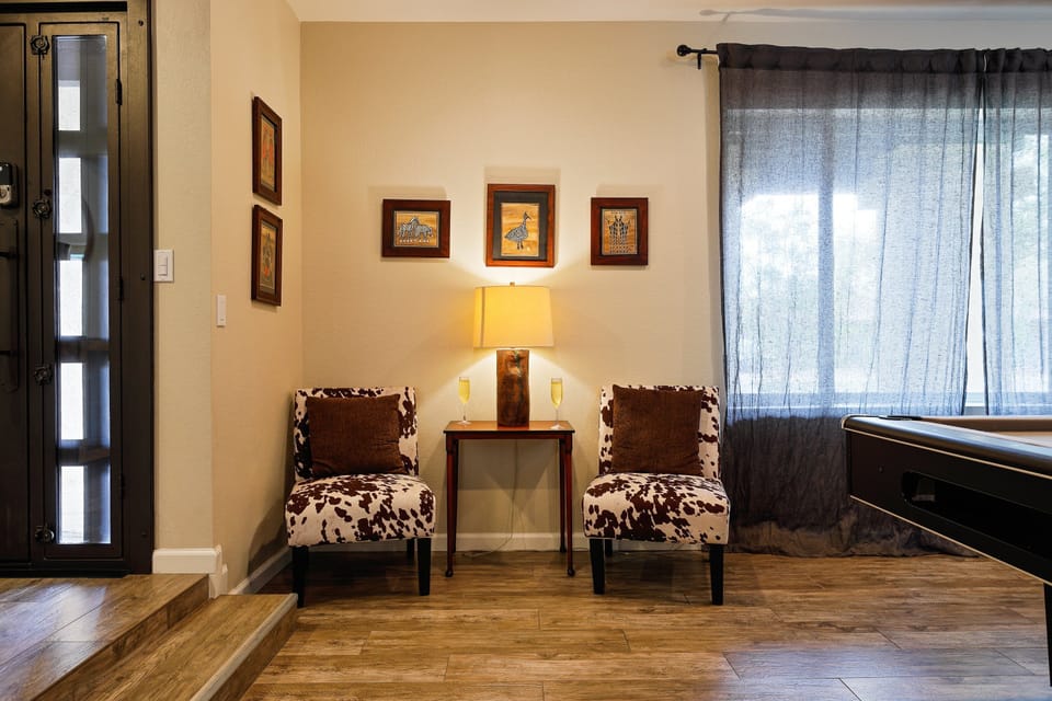 Game room with large smart TV, pool table, dart board, and additional seating.