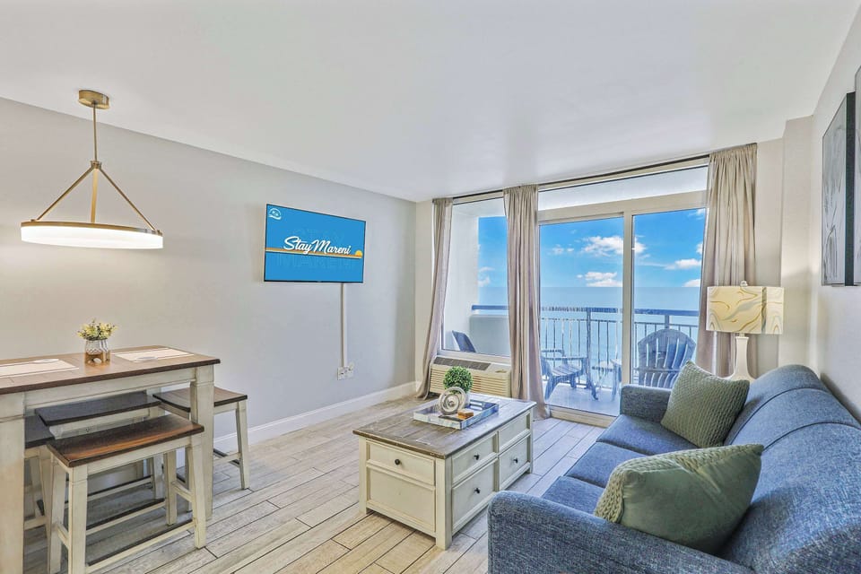 Relax in this bright and airy oceanfront living space featuring cozy seating, a dining nook, and stunning balcony views. The perfect Myrtle Beach retreat for dining, lounging, and soaking up those coastal vibes!