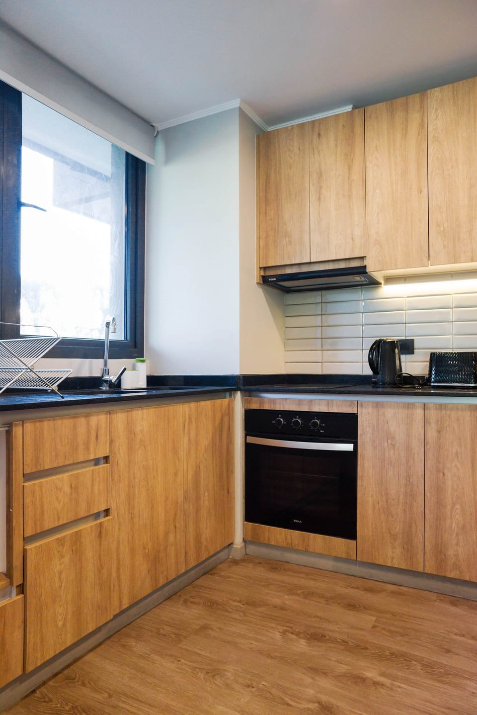 Bright, modern kitchen with sleek wooden finishes and ample natural light, ideal for culinary enthusiasts.