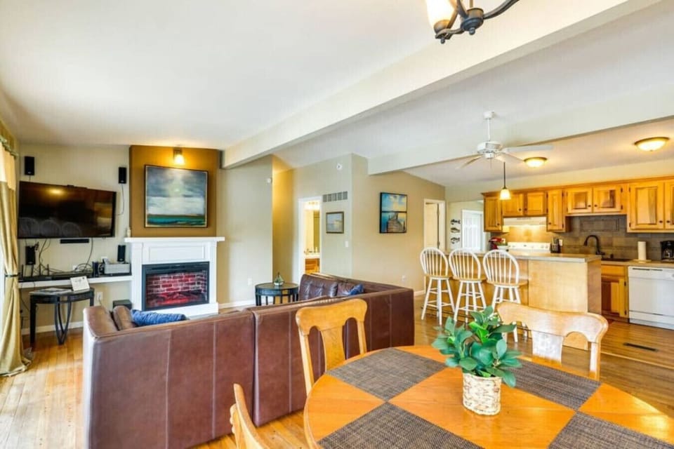Spacious open-concept living room featuring a cozy fireplace, large flat-screen TV, and comfortable leather sectional for ultimate relaxation.