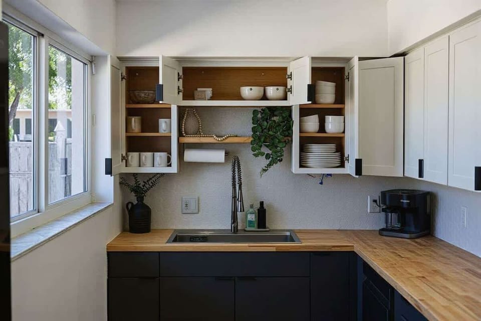 Kitchen detail: open shelving above the sink area, with black matte fixtures and a warm butcher block-style countertop.
