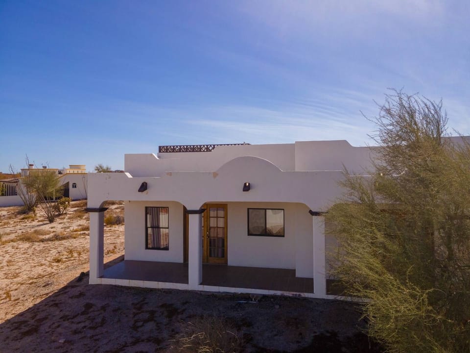This aerial drone shot shows the back of the property and the private patio with an outdoor dining area, near the heated El Cachanilla community pool