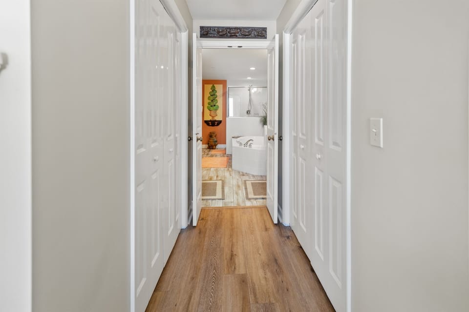 Step through crisp white hallways with warm hardwood floors leading to your luxurious bathroom retreat with elegant soaking tub.