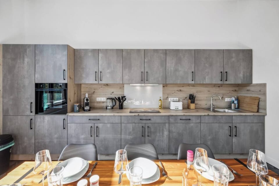 Moderne Einbauküche mit grauen Fronten, viel Stauraum und kompletter Ausstattung für entspanntes Kochen.