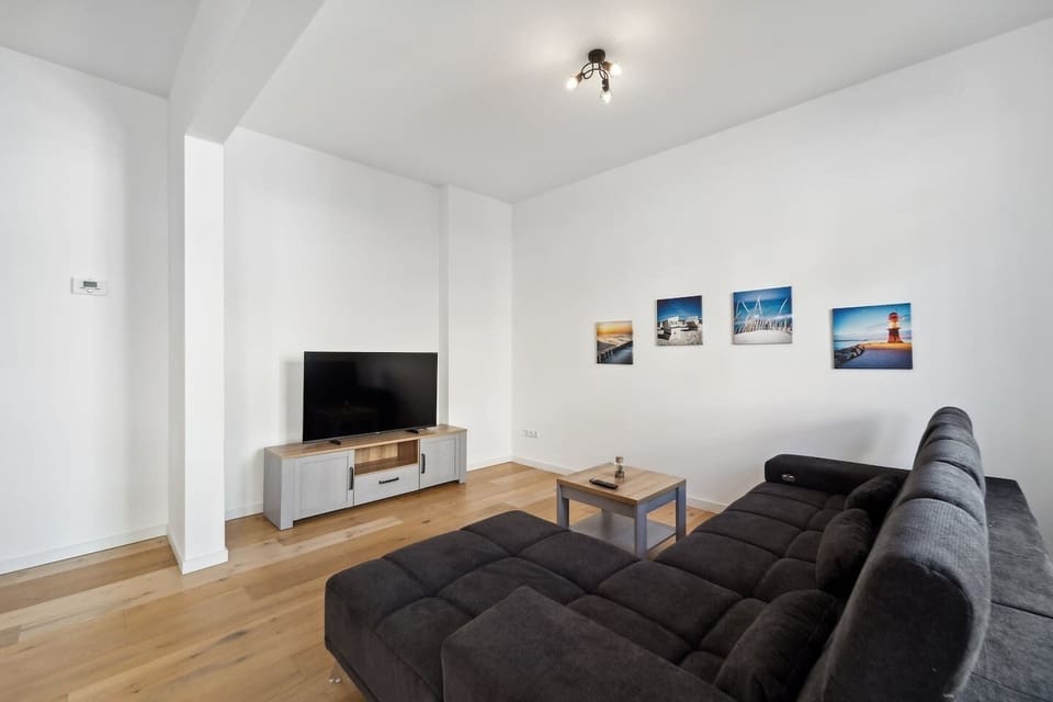 Das moderne Wohnzimmer überzeugt mit einem großen Sofa, Fernseher und geschmackvollen Wandbildern und lädt zu gemütlichen Filmabenden oder entspannten Stunden ein.