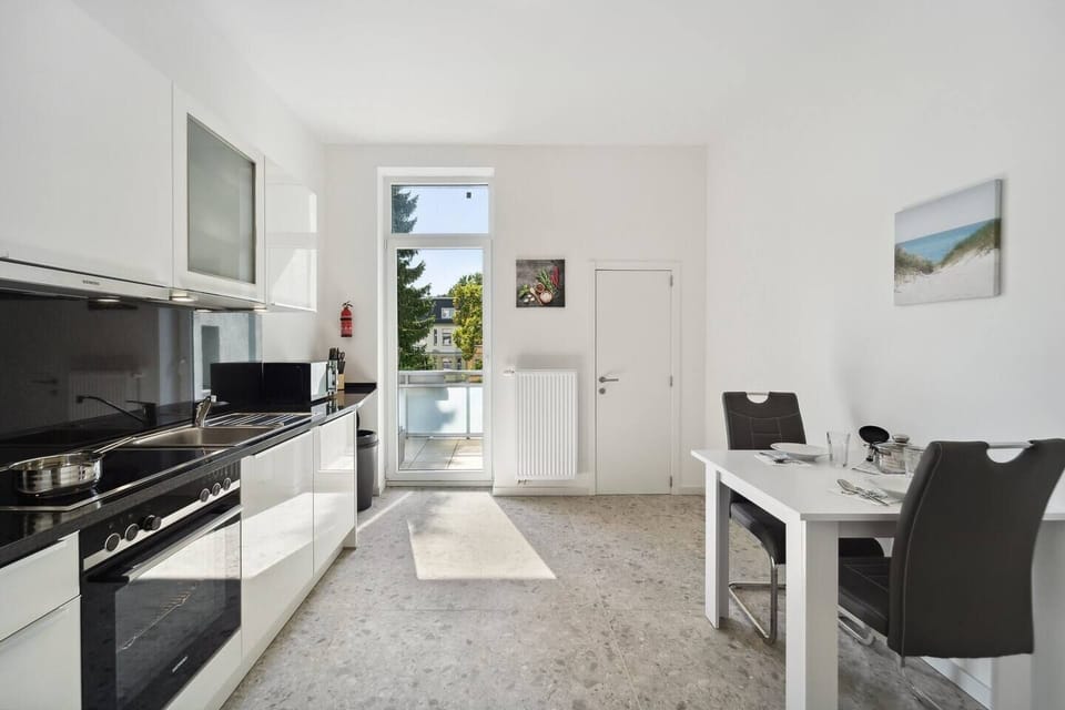 Die helle Küche ist mit modernen Geräten ausgestattet, bietet direkten Zugang zum Balkon und verfügt über einen kleinen Esstisch für gemeinsame Mahlzeiten.