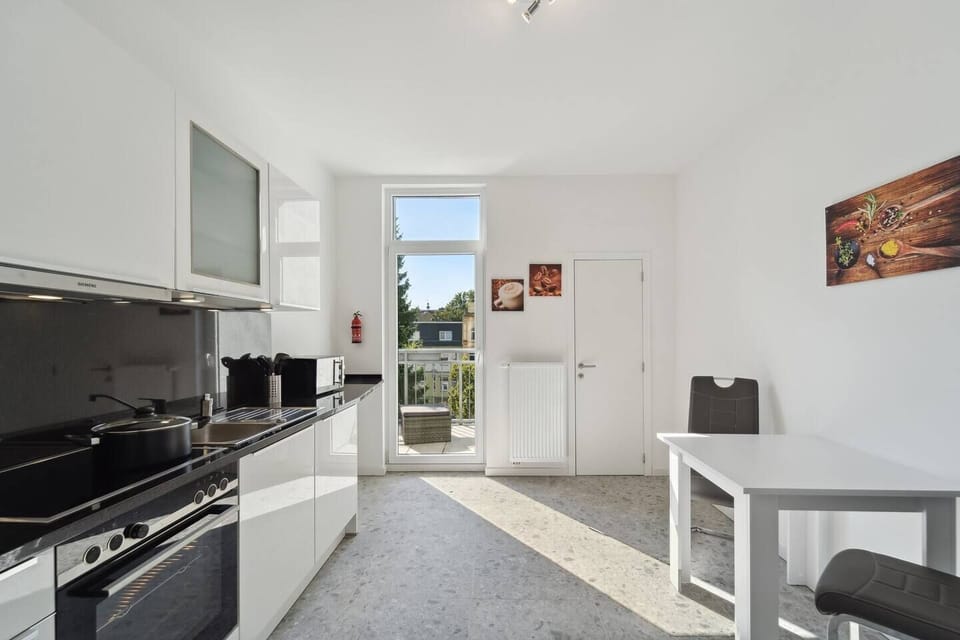 Die geräumige Küche überzeugt mit moderner Ausstattung, einem kleinen Essbereich und direktem Zugang zum Balkon.