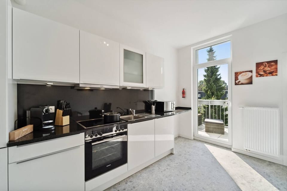Die helle, moderne Küche ist mit hochwertigen Geräten, viel Arbeitsfläche und direktem Zugang zum Balkon ausgestattet.