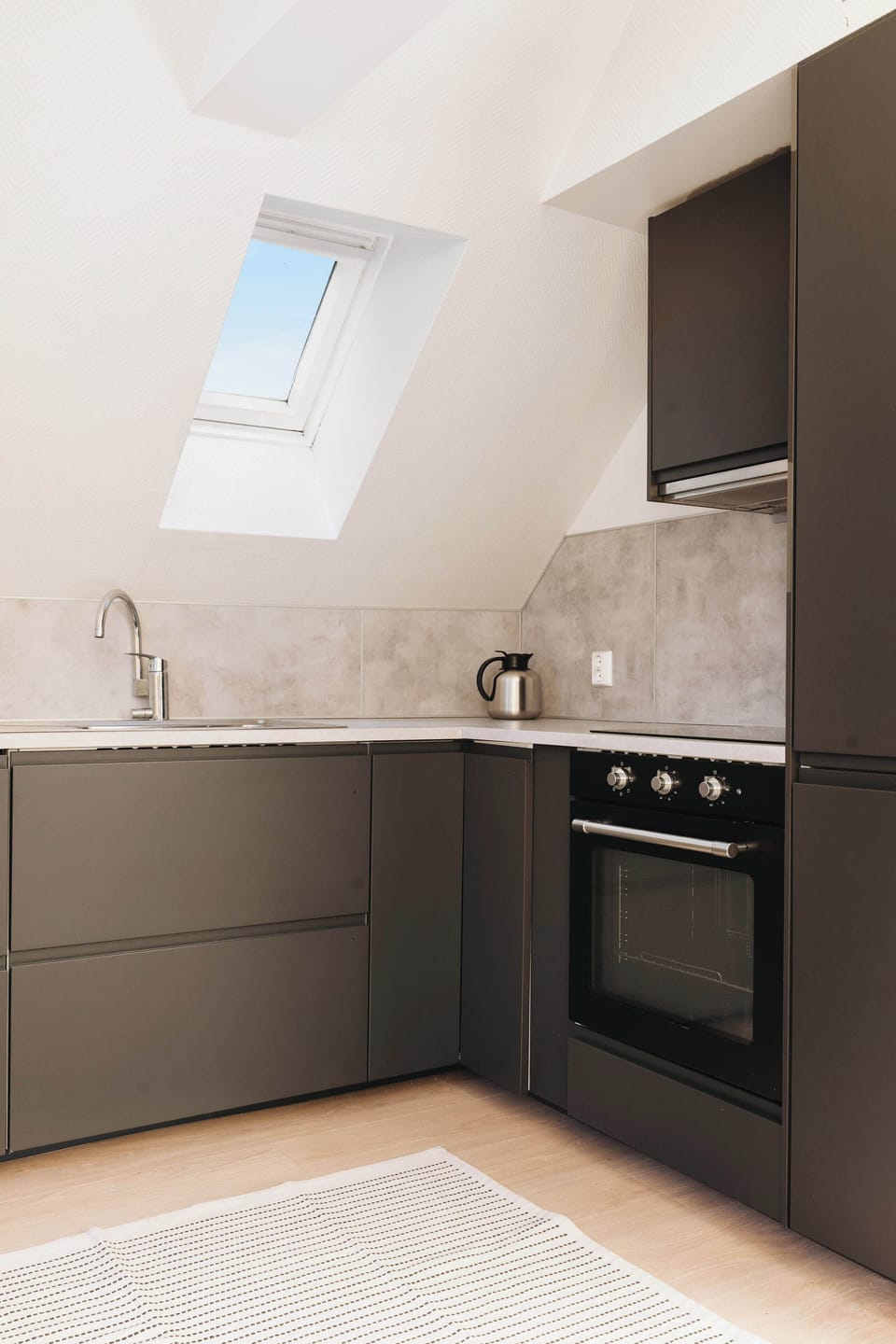 A modern kitchen, bathed in natural light, showcasing sleek dark cabinetry and a touch of airy charm.