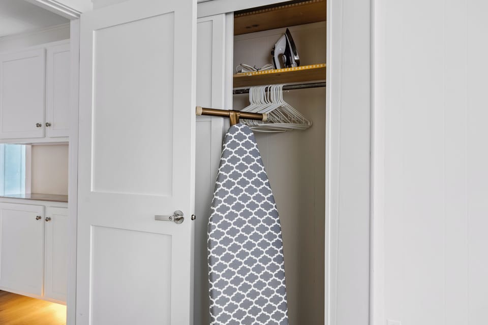 There is an ironing board and iron located in the closet of Bedroom #1 