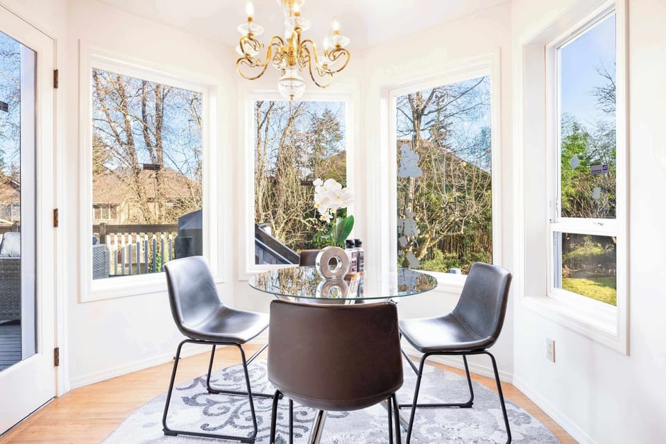A charming dining area surrounded by large windows, offering a perfect spot to start your day with a cup of coffee.