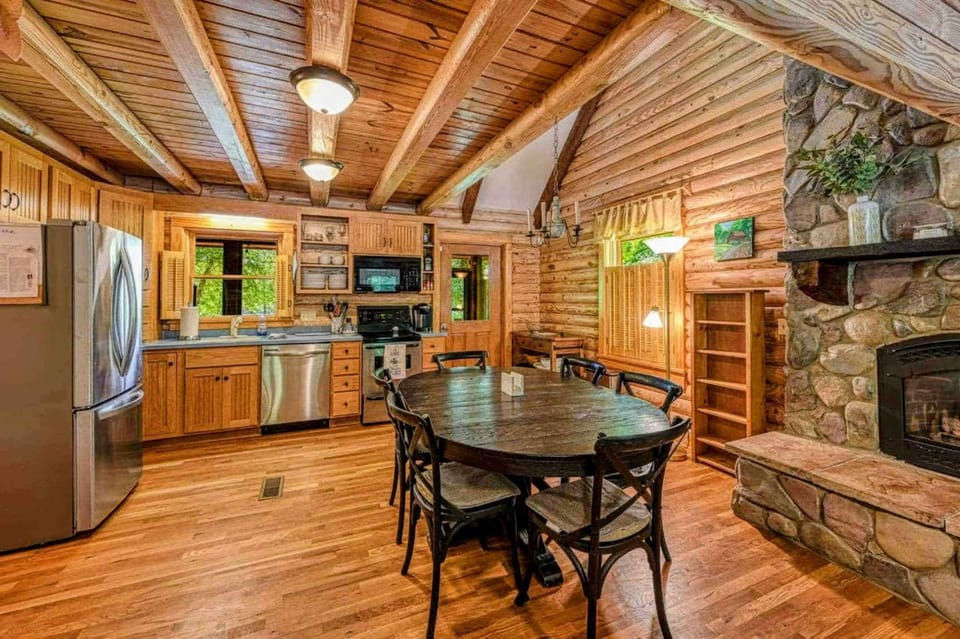 Step into this inviting log cabin kitchen, complete with modern amenities and a cozy dining area by the fireplace, perfect for gathering and creating memories.