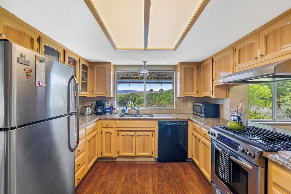 This kitchen space is centred around a large window above the sink that frames stunning views of the lush countryside, creating a bright and inspiring environment for any home chef.