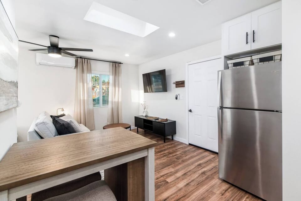 Bright, modern studio featuring a stainless steel fridge and mounted smart TV