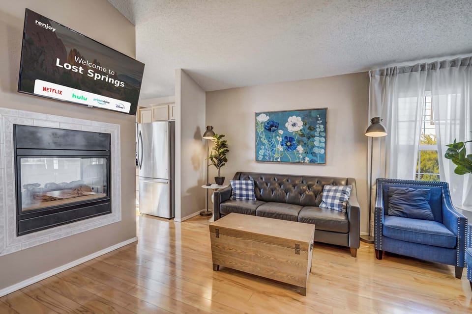 This bright and stylish living room offers a cozy fireplace, comfortable seating, and plenty of natural light for a warm and inviting atmosphere..

