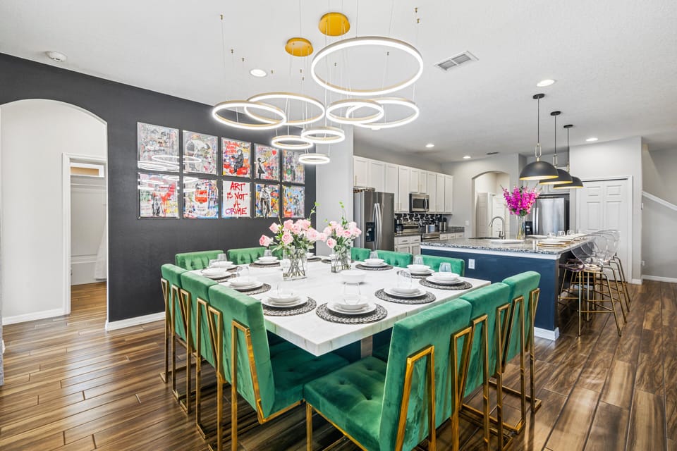 - Dining area with striking modern chandelier lighting  
- Large square dining table seats big family gatherings  
- Vibrant green chairs add bold style to every meal