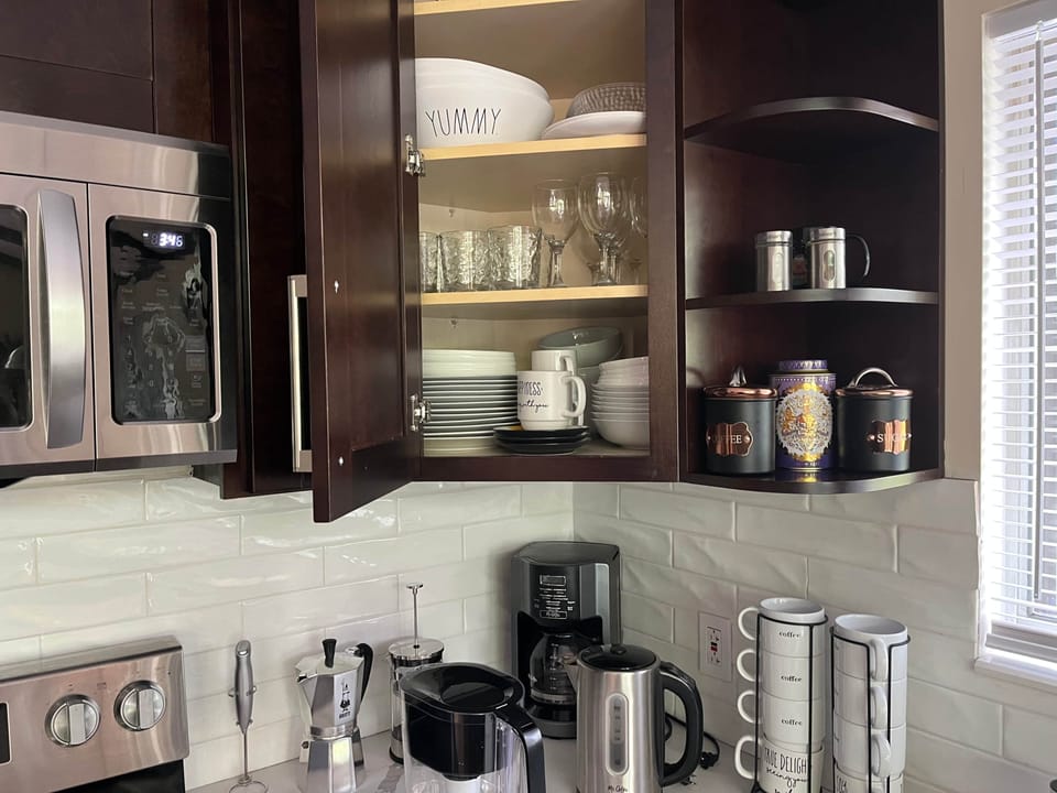 Fully stocked kitchen with dinnerware, glassware, mugs, and a coffee station for your convenience.
