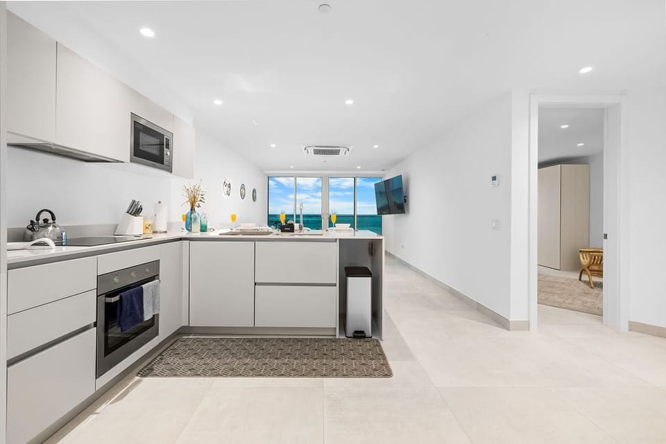 Your modern, fully-equipped kitchen opens to stunning turquoise ocean views. Bright, sleek, and ready for preparing fresh coastal meals, it's the heart of your beachside escape.