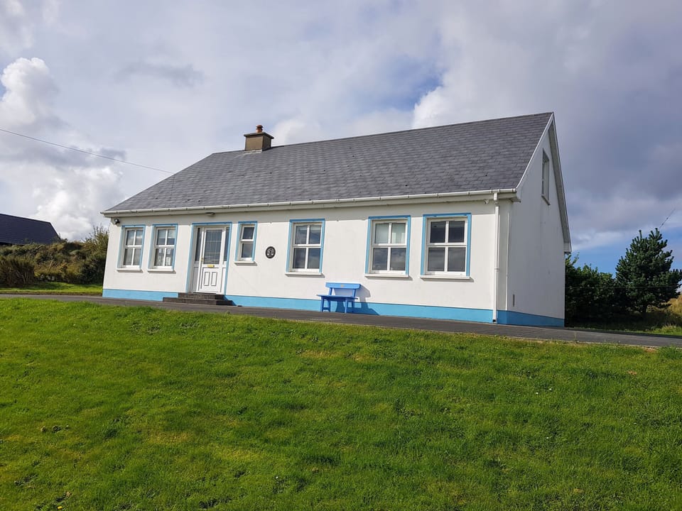 Front elevation of house, bench and huge garden.