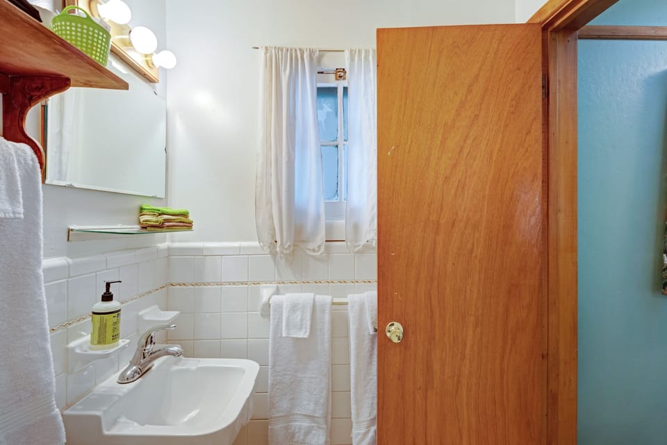 A compact bathroom featuring white tile wainscoting and a wooden door.