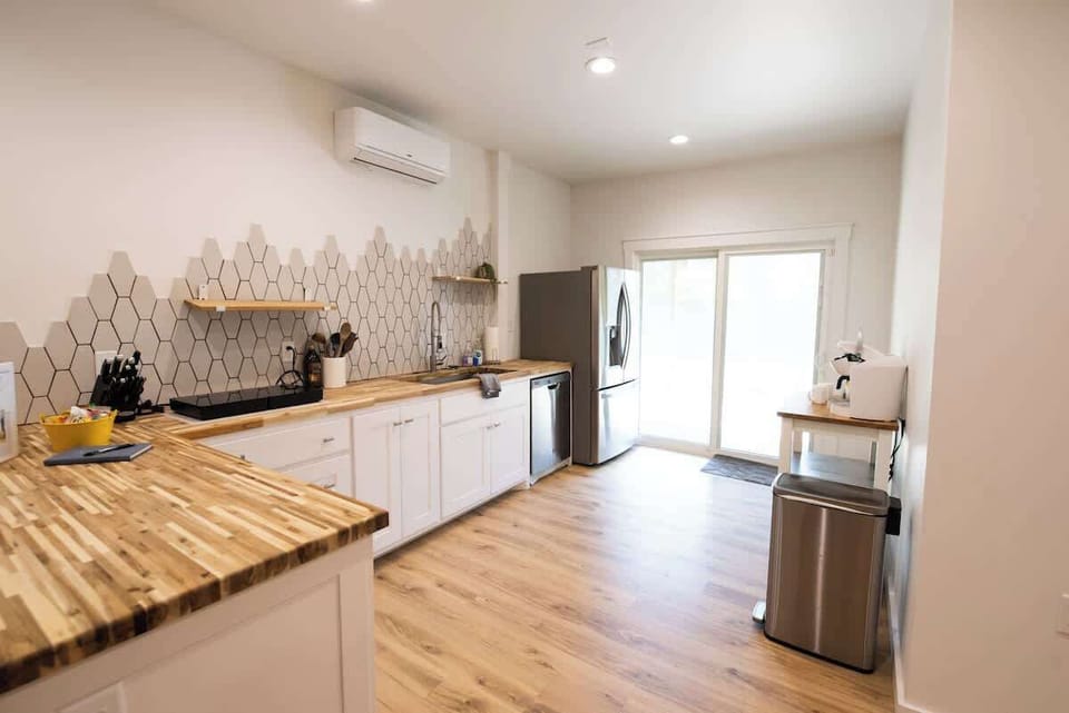 Cook and entertain in this spacious, modern kitchen featuring butcher block countertops, geometric backsplash tile, and stainless steel appliances.