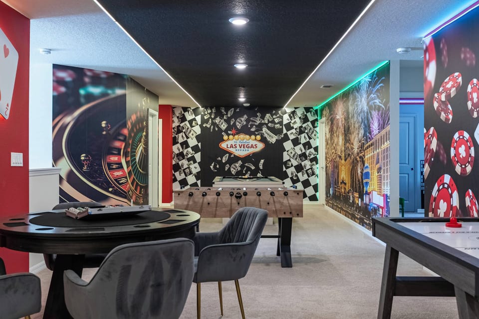 Step into a vibrant game room adorned with bold, casino-themed murals that set a lively tone. Enjoy friendly competition at the foosball table or gather around the sleek, round dining table, perfect for post-game chats.