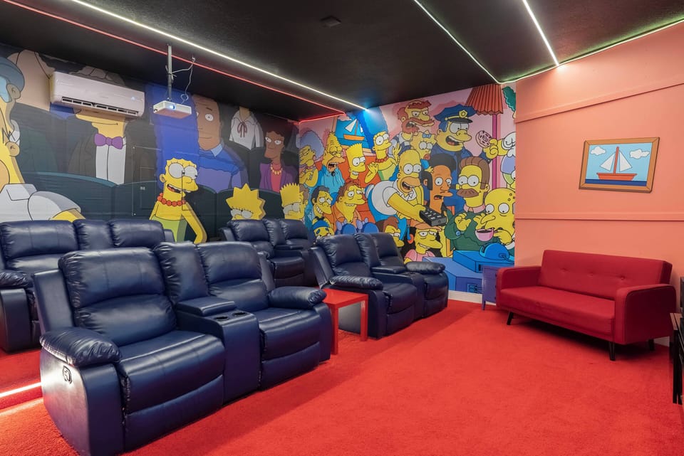 Enjoy a vibrant home theater featuring comfy blue recliners, a bright red carpet, and a lively mural. It's an ideal spot for cozy movie nights with friends or family, delivering a true cinematic experience.