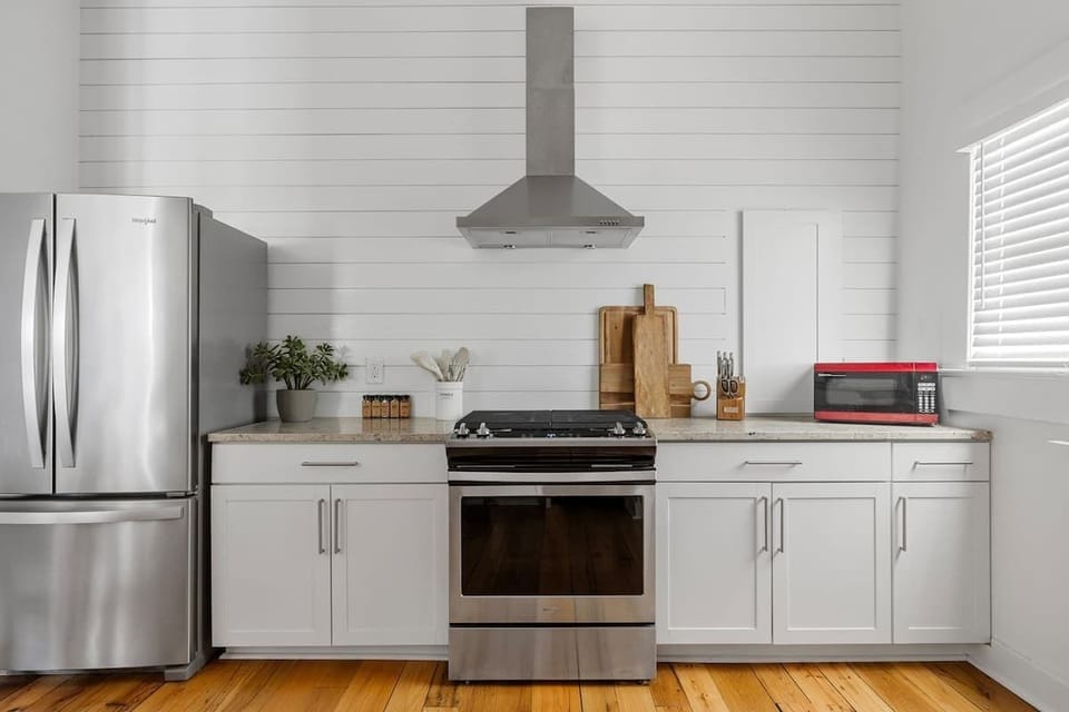 A bright, modern kitchen with stainless steel appliances, butcher block accents, and charming shiplap walls—perfect for brewing morning coffee or preparing a relaxed home-cooked meal after a day in Charleston.