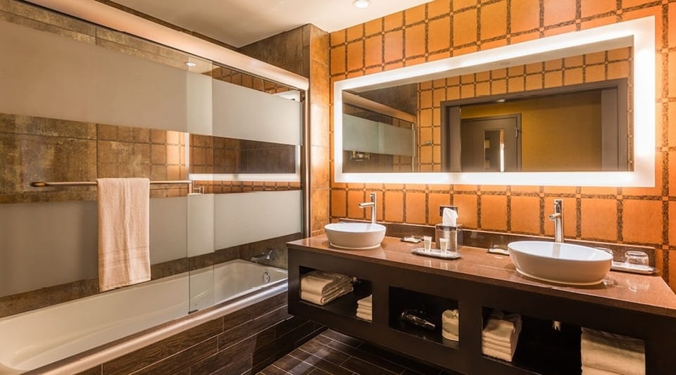 Unwind with a deep tub and glowing double-sink vanity.