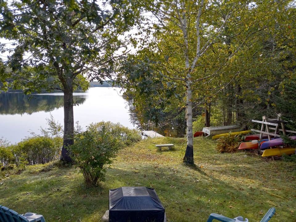 view from the door- fire pit, chairs, dock, kayaks