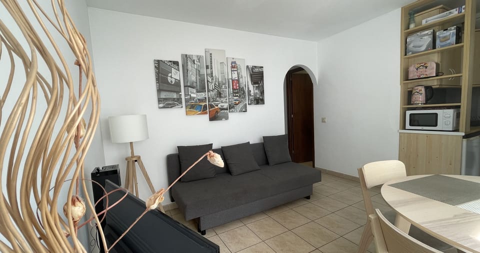 Living-dining room with sofa bed, dining table, and modern decor. Cozy and functional space.