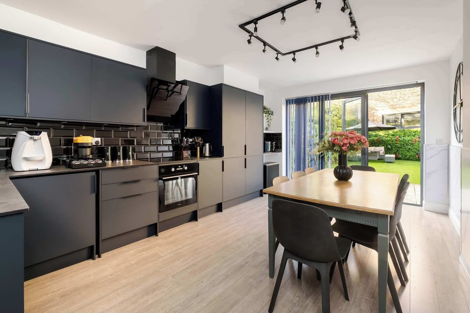 Full Kitchen | A kitchen fully equipped with everything needed for a comfortable stay, including a water dispenser, modern appliances, full cookware, and a dining table. The space flows directly into the private garden for a smooth and social layout.