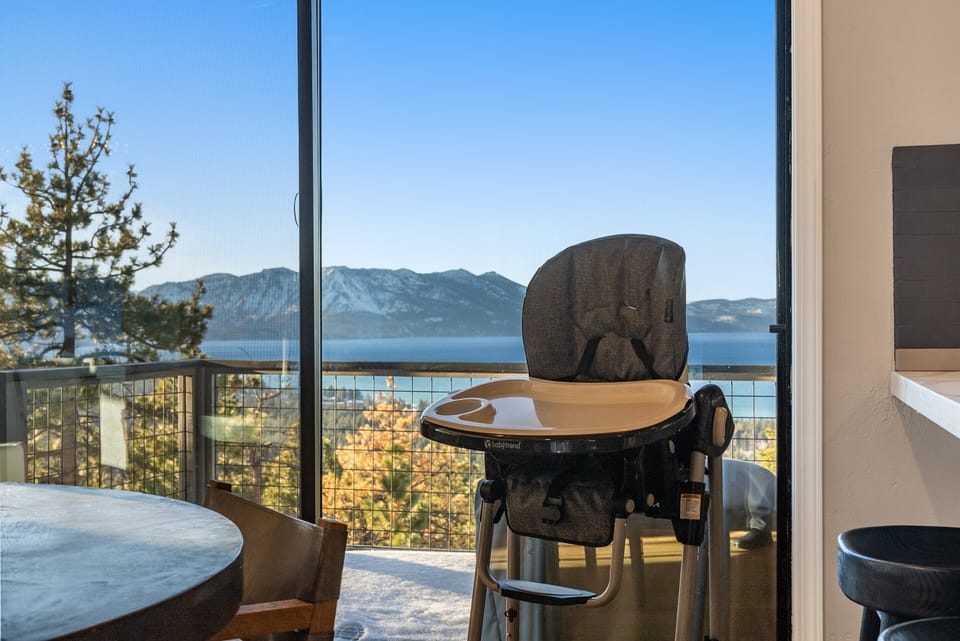 Dining area with round table, high chair, sliding door, lake view, and mountain view.