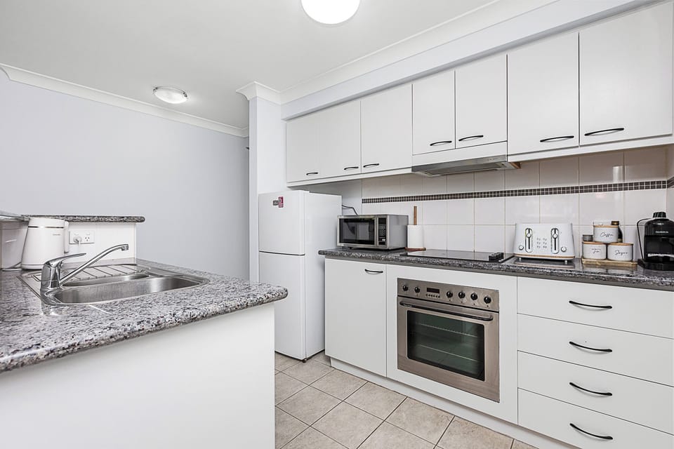 Prepare meals in a bright white kitchen, featuring modern appliances and ample counter space.