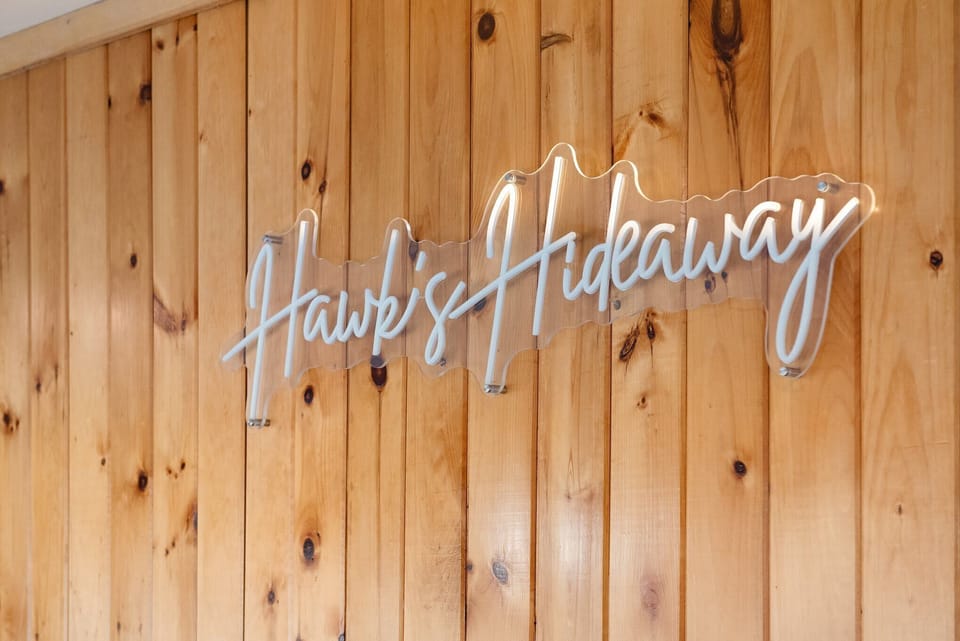 Welcome to Hawk’s Hideaway
A warm wood wall and custom sign set the tone for your rustic mountain retreat.