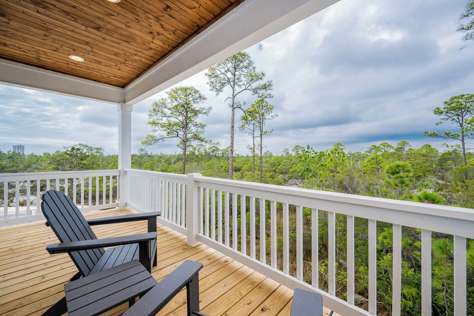 Relax on the spacious deck with black Adirondack chairs, enjoying serene views of lush greenery and tall pines