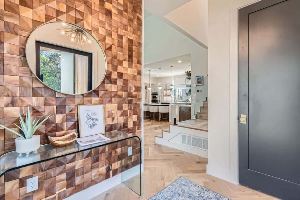 Stylish and inviting entryway with a modern wood accent wall, leading into a bright, open-concept kitchen and living space.