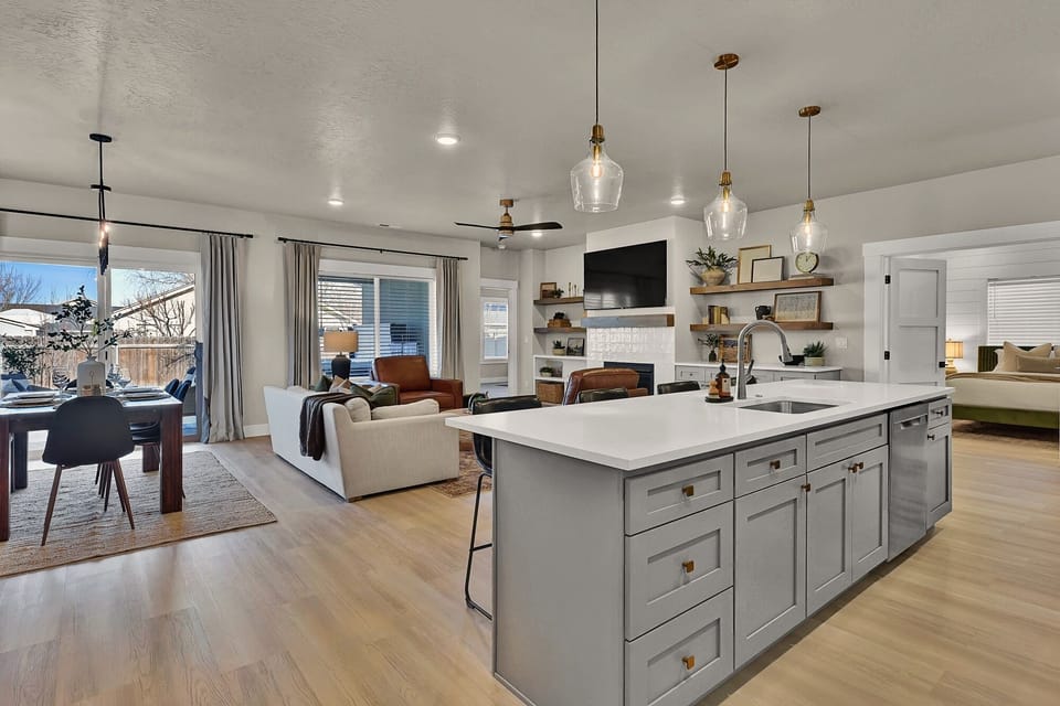 This open-concept kitchen, living, and dining area is bright and inviting, with large windows that fill the space with natural light—perfect for gathering and making memories.