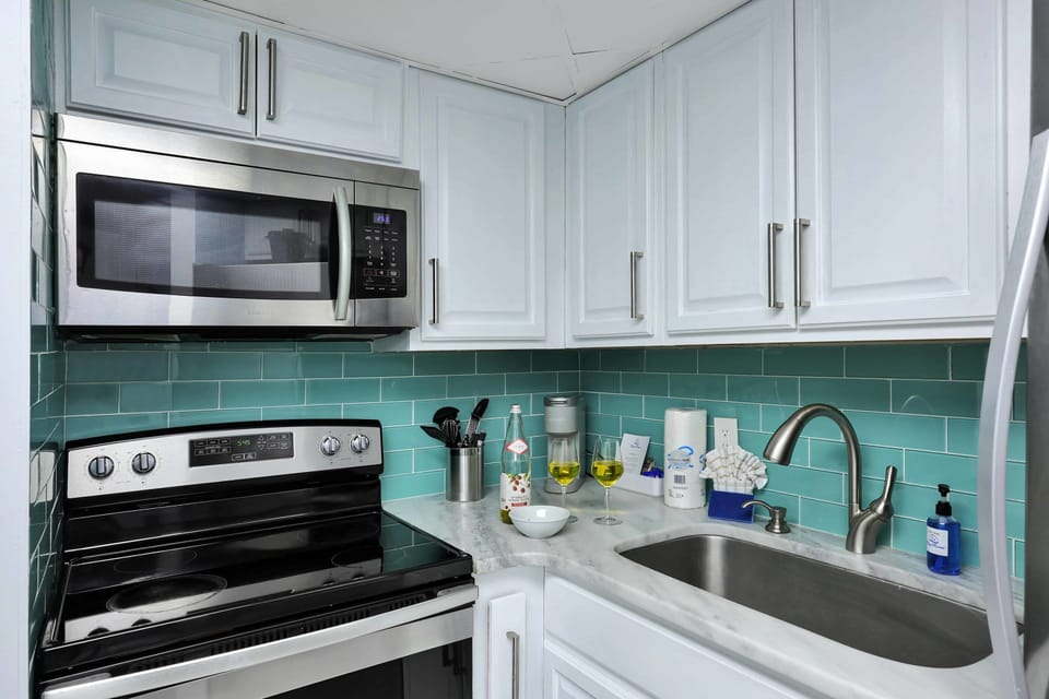 Whip up your favorite meals in this modern, fully equipped kitchen with stainless steel appliances and coastal-chic backsplash! Perfect for beach days and cozy nights in.
