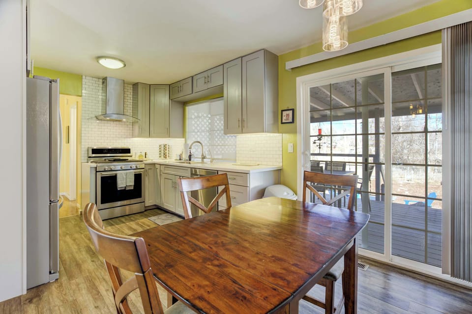 Warm wood dining table beside a bright, streamlined kitchen—set out breakfast, prep and cook with everything close at hand, then slide the glass door open for easy back-and-forth between meals and fresh air.